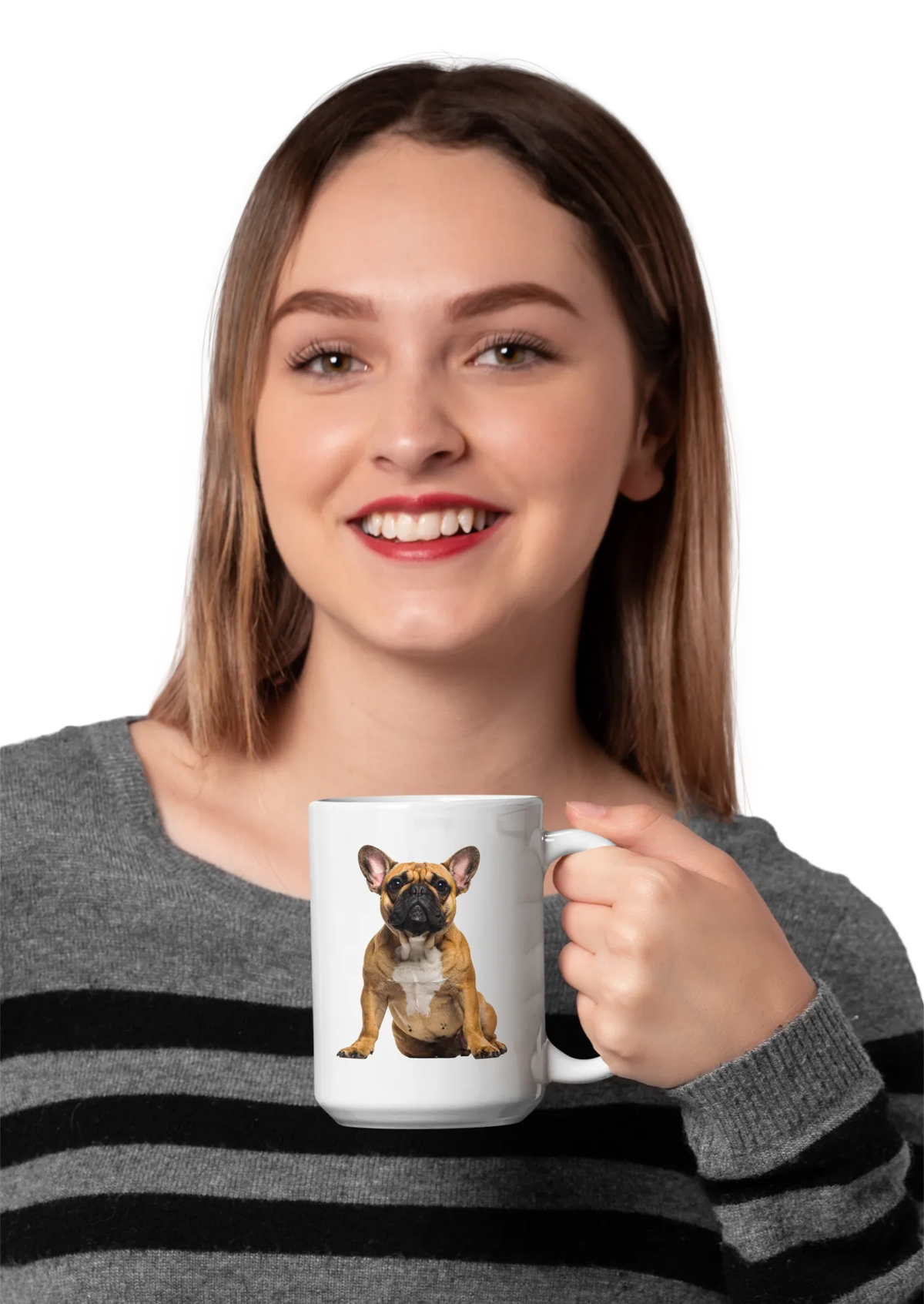 A smiling woman with light brown hair holds a white ceramic mug featuring a printed illustration of a French bulldog. She is wearing a gray and black striped knit sweater against a plain white background.