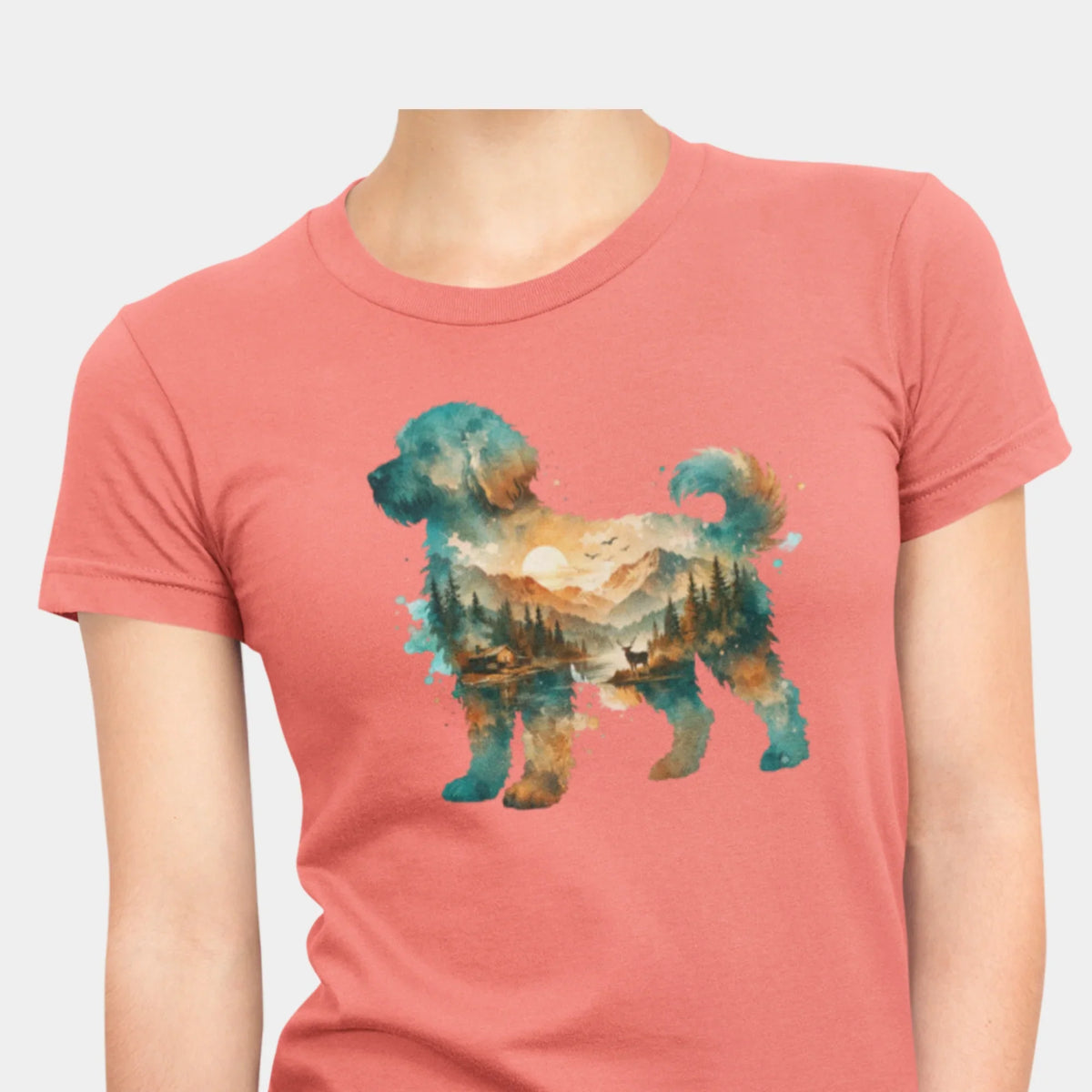 A woman wearing a coral silk colored short-sleeve crewneck t-shirt featuring a watercolor-style graphic of a goldendoodle dog silhouette filled with a scenic landscape of mountains, trees, and a lake.
