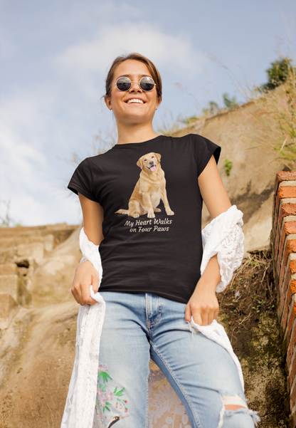 A woman wearing a black graphic t-shirt with a Golden Retriever print and the text 'My Heart Walks on Four Paws', paired with light blue jeans and sunglasses, standing outdoors against a rustic stone wall.
