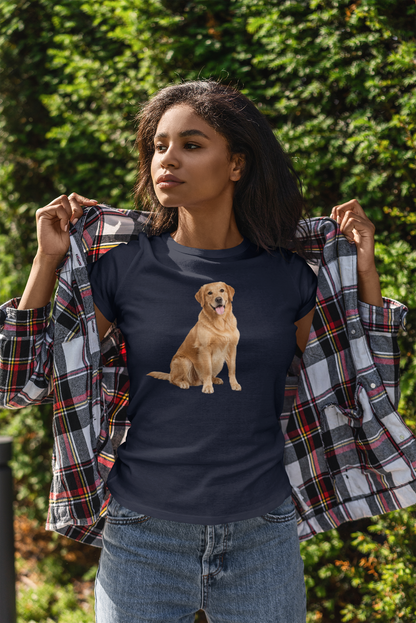 A woman outdoors wearing a navy blue t-shirt with a graphic of a golden retriever dog, holding open a plaid flannel shirt over her shoulders. She is wearing blue jeans, with a background of green foliage.