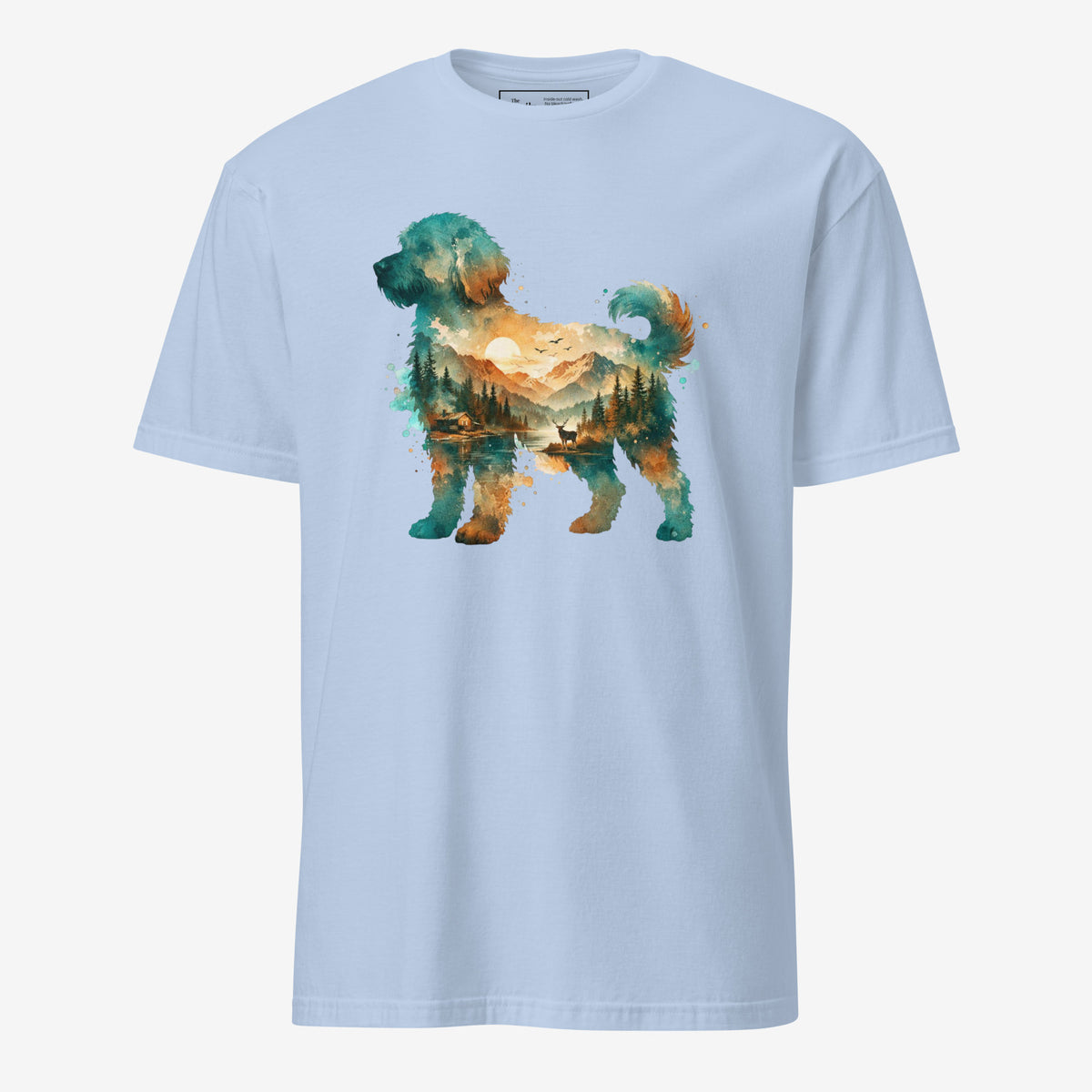 A light blue short-sleeve crewneck t-shirt featuring a watercolor-style graphic of a goldendoodle dog silhouette filled with a scenic landscape of mountains, trees, and a lake.
