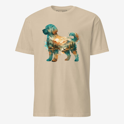 A sand colored short-sleeve crewneck t-shirt featuring a watercolor-style graphic of a goldendoodle dog silhouette filled with a scenic landscape of mountains, trees, and a lake.